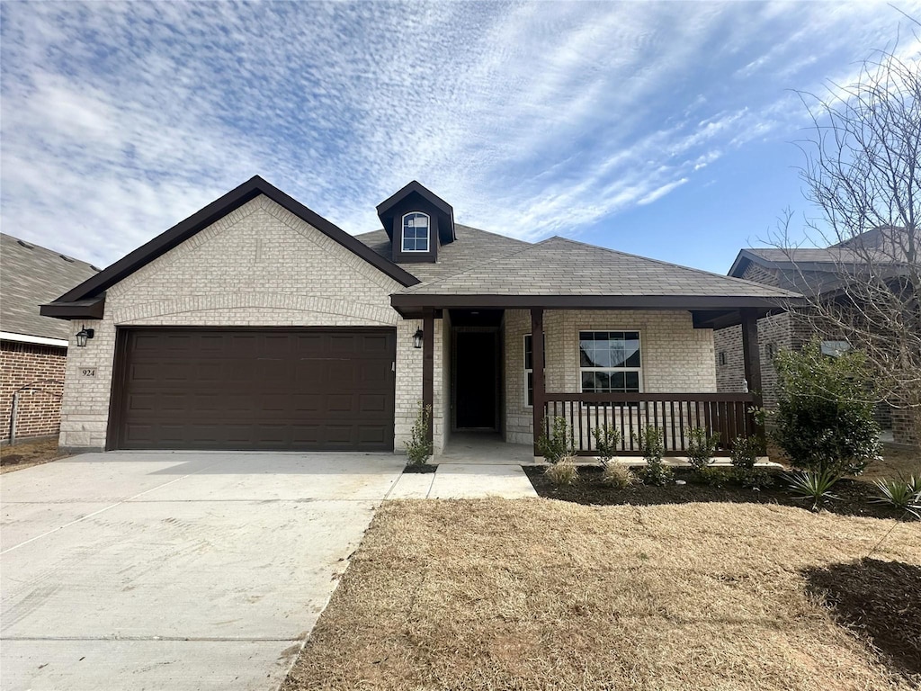 ranch-style house featuring brick siding, roof with shingles, a porch, concrete driveway, and an attached garage