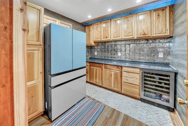 kitchen featuring beverage cooler, dark countertops, light brown cabinets, and freestanding refrigerator