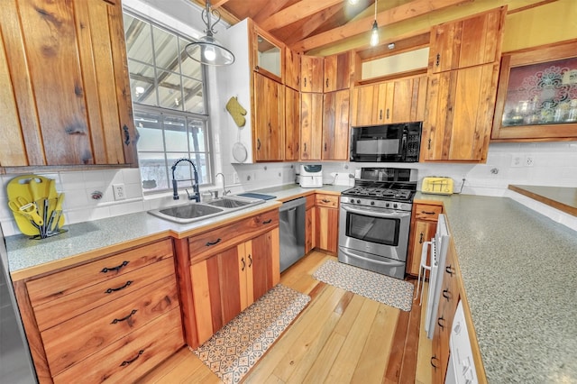 kitchen featuring appliances with stainless steel finishes, pendant lighting, light countertops, and a sink