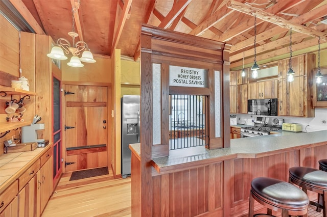 kitchen with black microwave, range, decorative light fixtures, and stainless steel fridge with ice dispenser