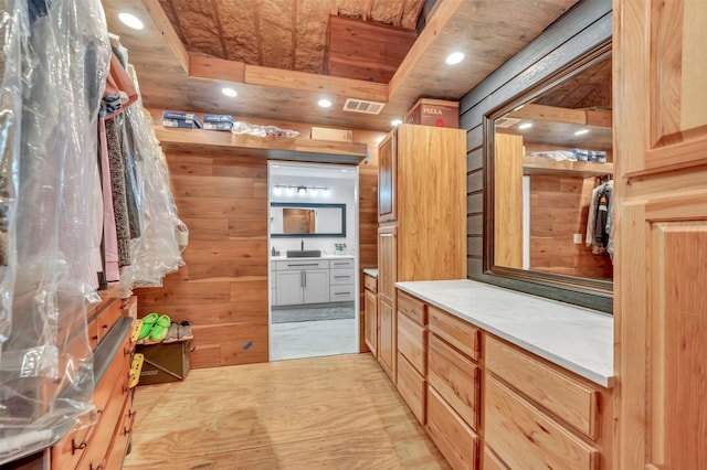 bathroom featuring a closet, vanity, visible vents, and wooden walls