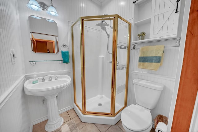 bathroom with a stall shower, a sink, toilet, and tile patterned floors