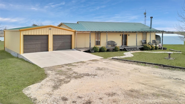 view of front of home featuring a porch, an attached garage, metal roof, driveway, and a front lawn