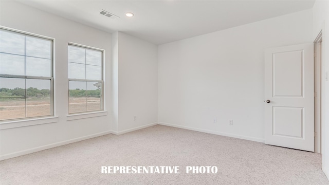 spare room featuring light carpet, visible vents, baseboards, and recessed lighting