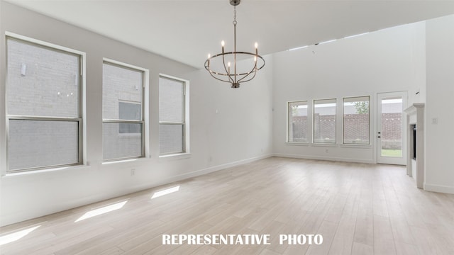 unfurnished room featuring a chandelier, light wood-style flooring, and baseboards