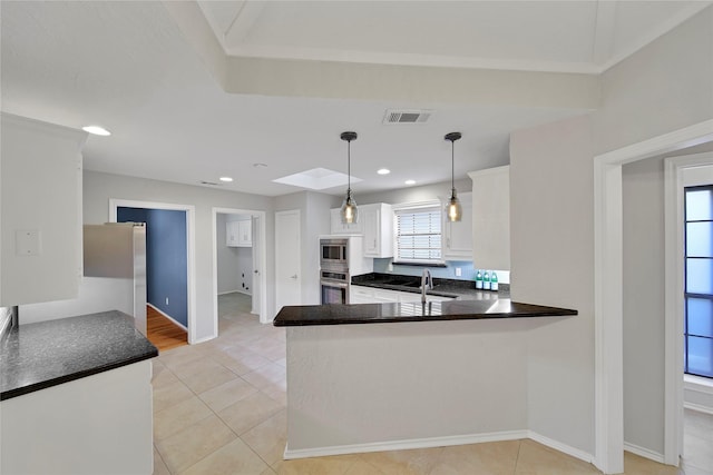 kitchen with pendant lighting, stainless steel appliances, visible vents, white cabinets, and a peninsula