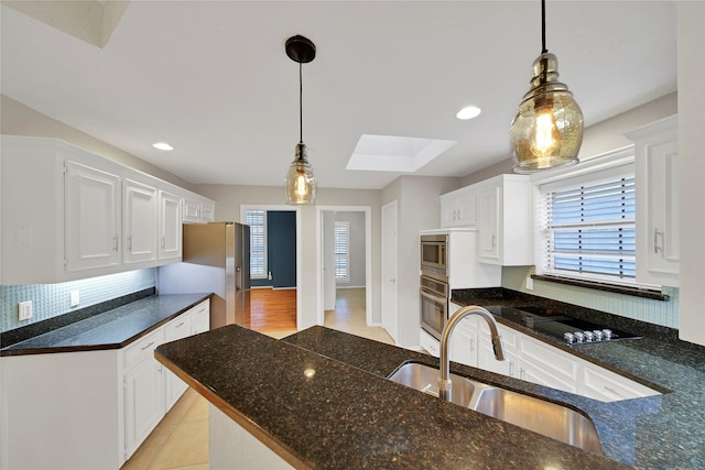 kitchen featuring white cabinets, appliances with stainless steel finishes, pendant lighting, and a sink