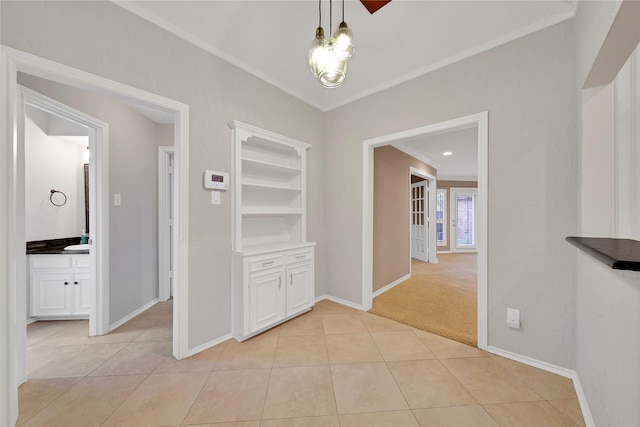 corridor featuring light tile patterned floors, baseboards, and crown molding