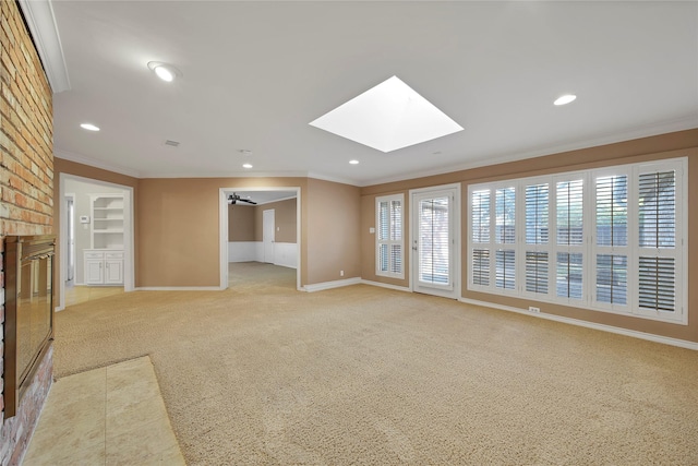 unfurnished living room featuring light carpet, ornamental molding, a skylight, and baseboards