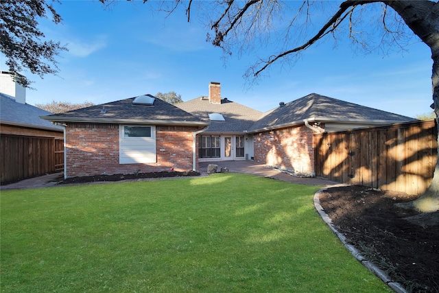 rear view of property featuring a chimney, fence, a lawn, and brick siding