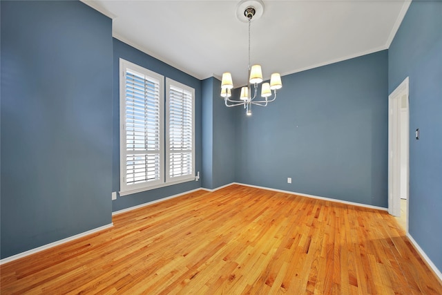 unfurnished room with a chandelier, light wood-style floors, ornamental molding, and baseboards