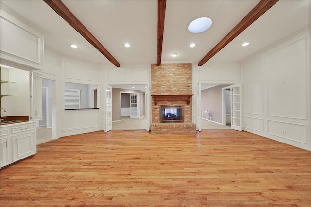 unfurnished living room with a fireplace, a sink, beam ceiling, and a decorative wall