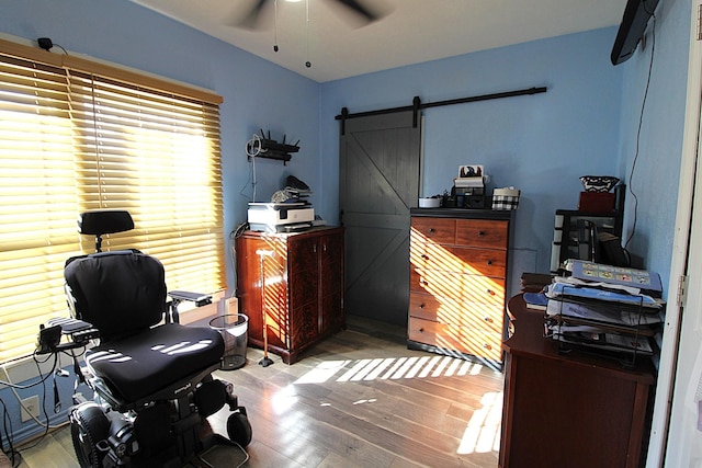 home office featuring a barn door, a ceiling fan, and wood finished floors