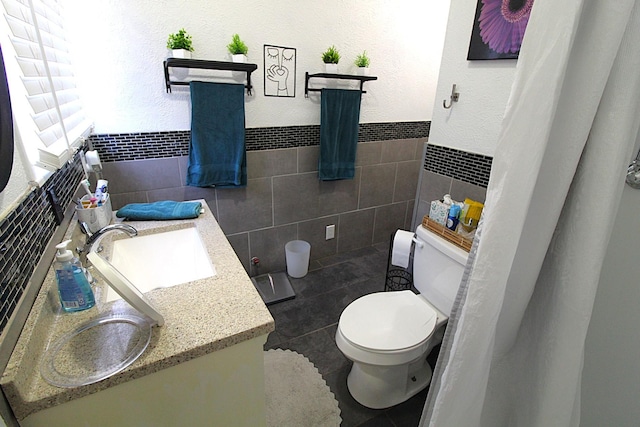 bathroom with toilet, vanity, and tile walls