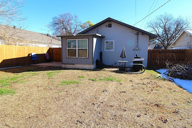 rear view of property featuring a yard, a fenced backyard, and a patio