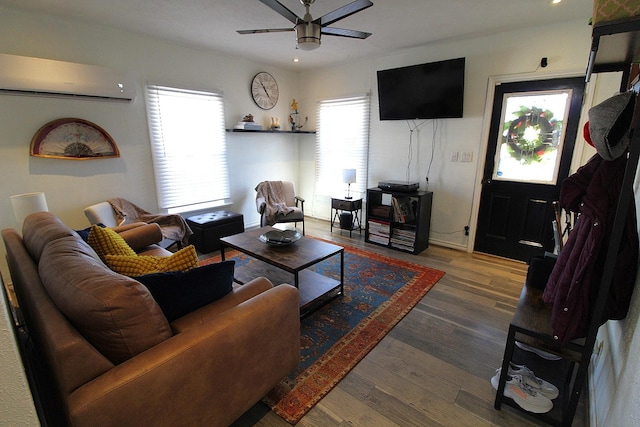 living room with a ceiling fan, an AC wall unit, and wood finished floors