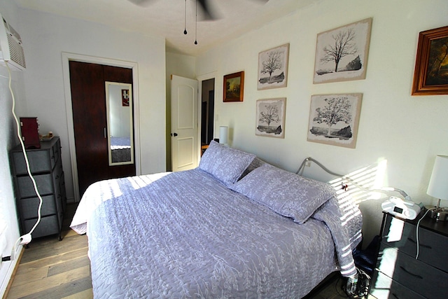 bedroom featuring a ceiling fan, an AC wall unit, and wood finished floors