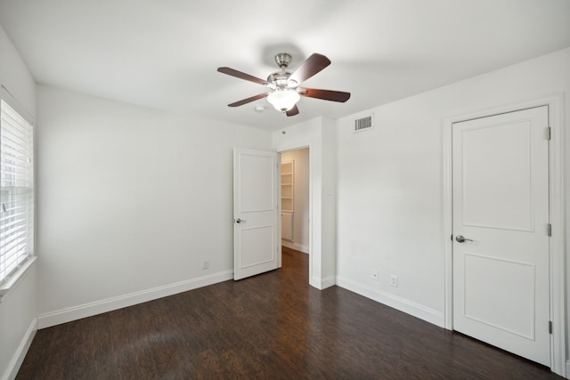 unfurnished bedroom with visible vents, dark wood finished floors, baseboards, and multiple windows