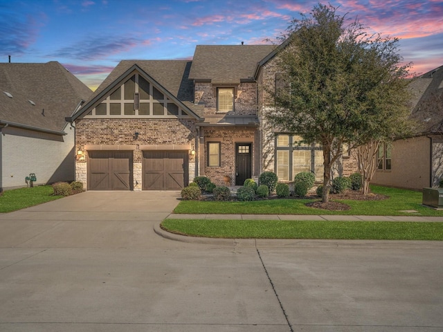 view of front of property featuring a garage, brick siding, driveway, stone siding, and roof with shingles