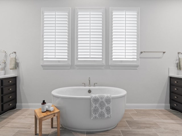 full bathroom featuring a freestanding tub, vanity, and baseboards