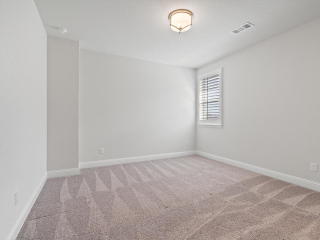 empty room with carpet floors, visible vents, and baseboards