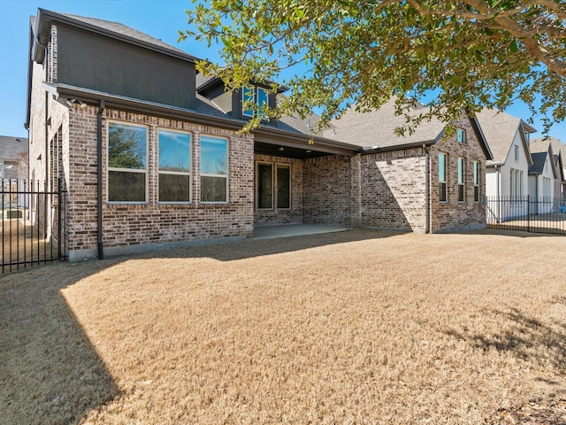 back of property featuring a lawn, fence, a patio, and brick siding