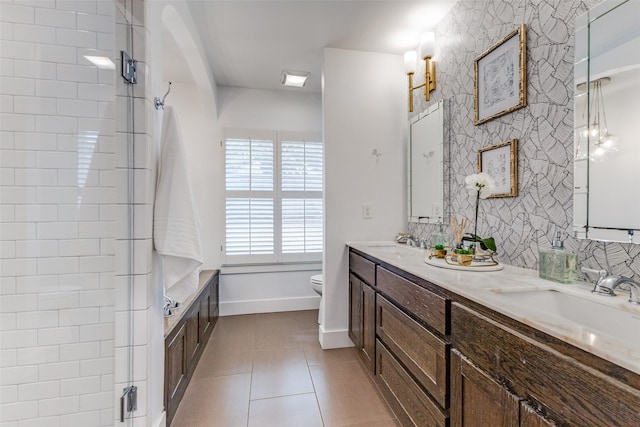 bathroom featuring double vanity, toilet, a sink, tile patterned flooring, and wallpapered walls