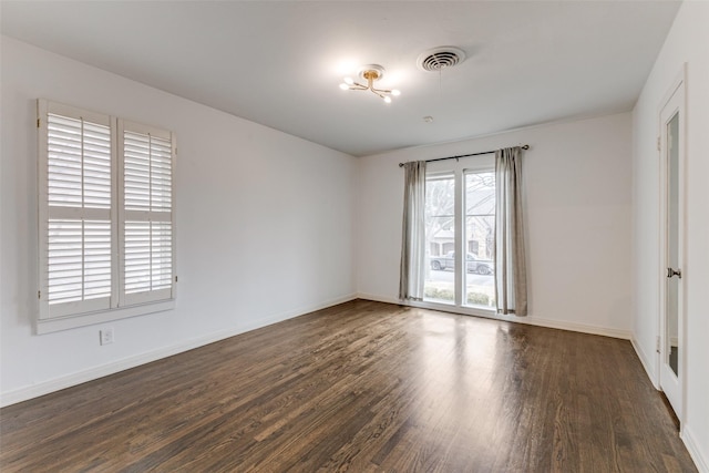 spare room featuring baseboards, visible vents, and wood finished floors