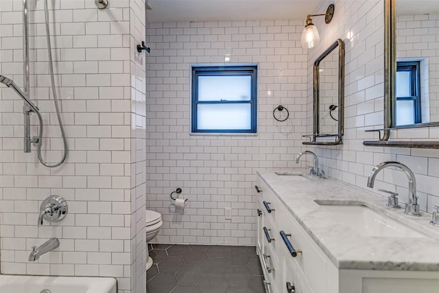 bathroom featuring tile patterned flooring, a sink, tile walls, and toilet