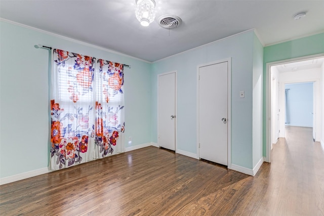 bedroom featuring baseboards, crown molding, visible vents, and wood finished floors