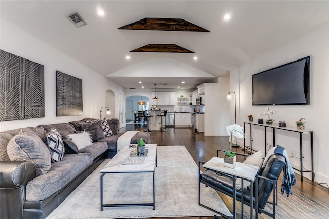 living room featuring vaulted ceiling, visible vents, dark wood finished floors, and arched walkways