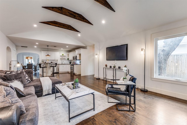 living room featuring arched walkways, dark wood finished floors, baseboards, and recessed lighting