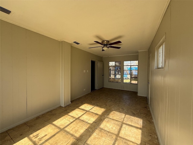 spare room featuring a ceiling fan, baseboards, visible vents, and crown molding