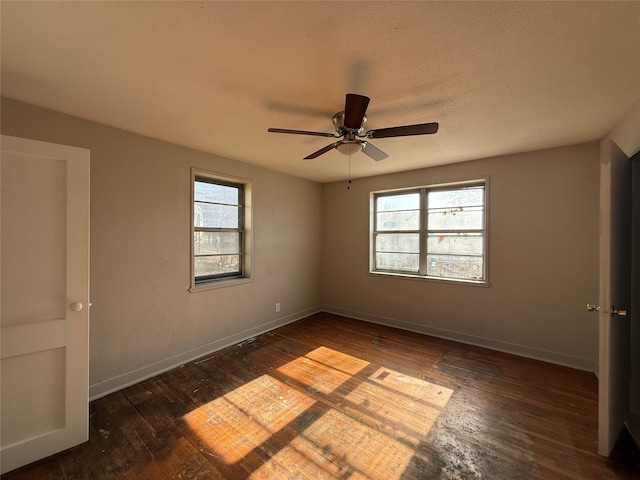 spare room featuring dark wood-style floors, baseboards, and a healthy amount of sunlight