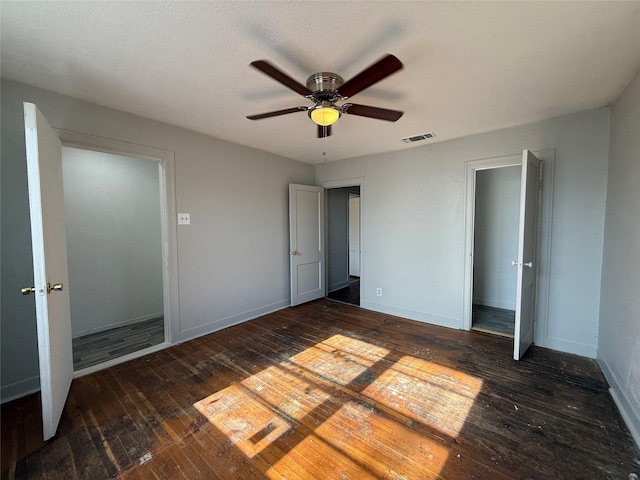 unfurnished bedroom featuring dark wood-type flooring, visible vents, ceiling fan, and baseboards