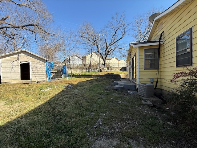 view of yard featuring an outdoor structure, central AC unit, and a shed