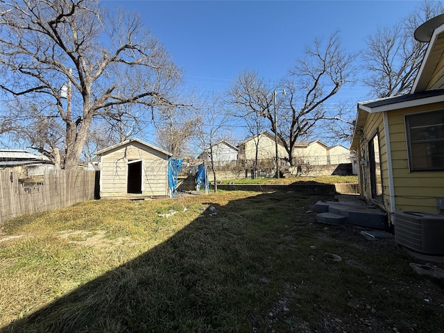 view of yard with a storage shed, an outbuilding, a fenced backyard, and central air condition unit