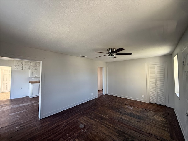 unfurnished room featuring dark wood-style floors, ceiling fan, baseboards, and a textured ceiling