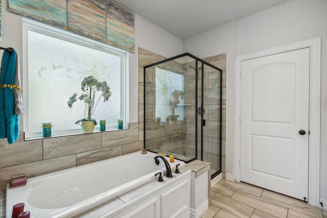 bathroom featuring a stall shower, a healthy amount of sunlight, and a bath