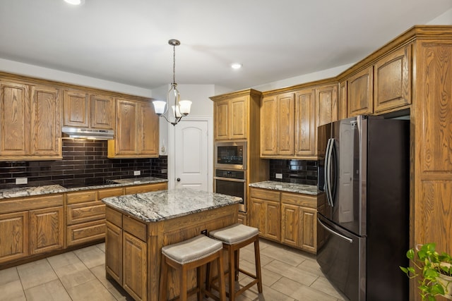 kitchen with brown cabinets, under cabinet range hood, stainless steel appliances, and a center island