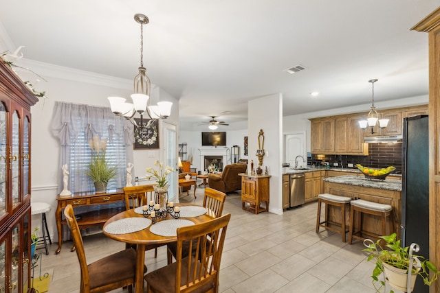 dining space featuring a fireplace, light tile patterned floors, visible vents, ornamental molding, and ceiling fan with notable chandelier