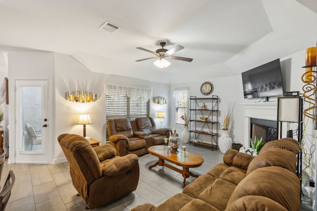 living area featuring ceiling fan, a fireplace, visible vents, and baseboards