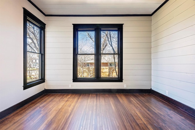 spare room with dark wood-type flooring, a healthy amount of sunlight, and baseboards