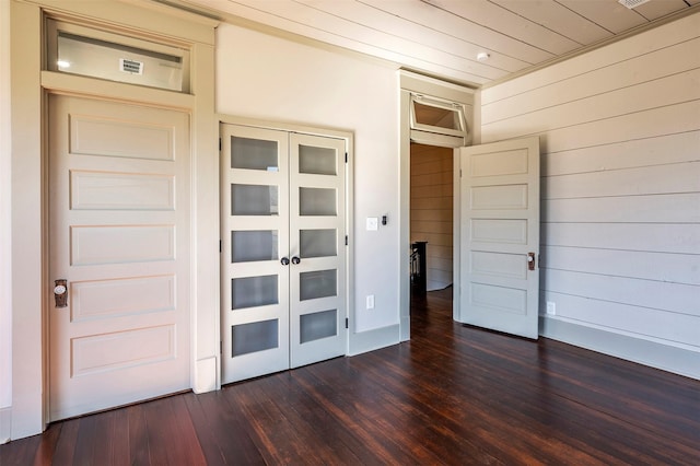 unfurnished bedroom featuring dark wood-style floors, a closet, and baseboards