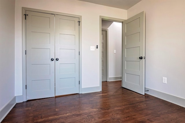 unfurnished bedroom featuring dark wood-type flooring, a closet, and baseboards