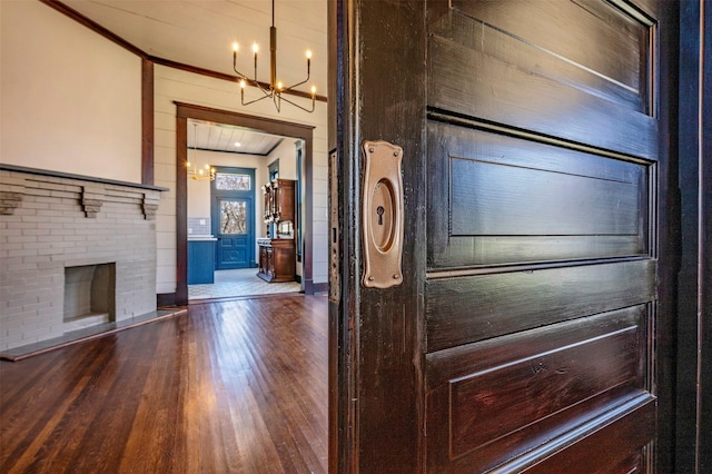 interior space with crown molding, a fireplace, a chandelier, and wood finished floors