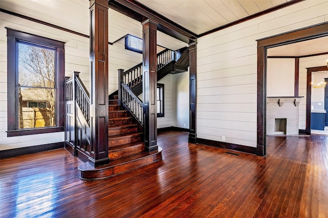 interior space featuring visible vents, dark wood-style flooring, stairs, wood walls, and a fireplace