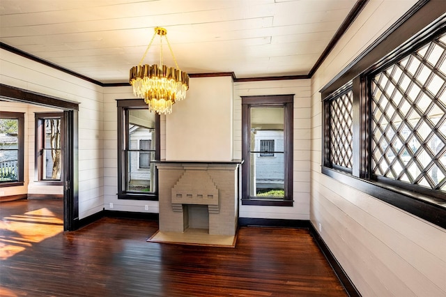 interior space with baseboards, a notable chandelier, ornamental molding, and dark wood-type flooring