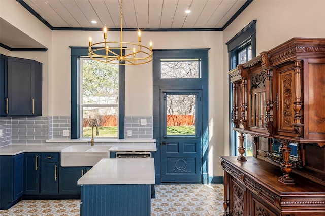 kitchen featuring crown molding, light countertops, hanging light fixtures, and a sink