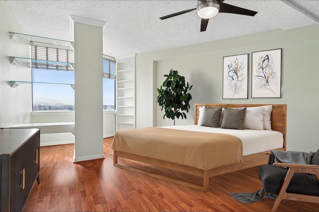 bedroom with baseboards, wood finished floors, ceiling fan, and a textured ceiling